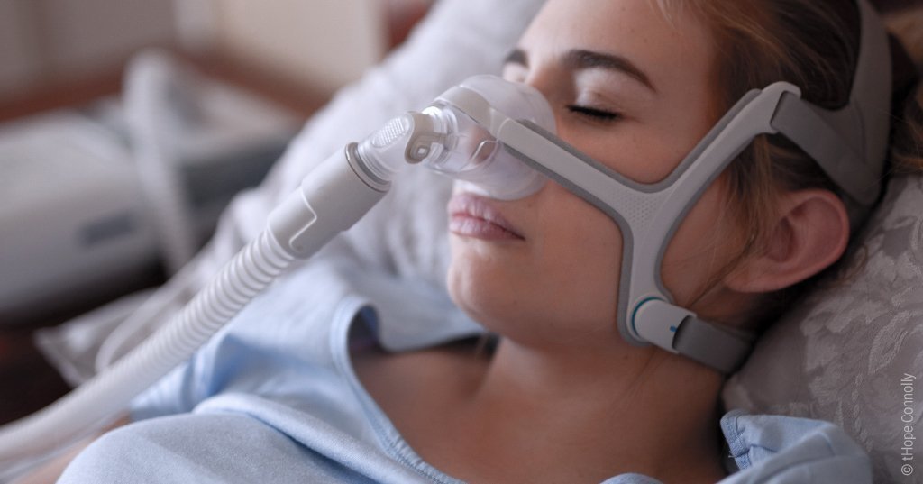 Foto: Eine schlafende Person trägt eine CPAP-Maske.