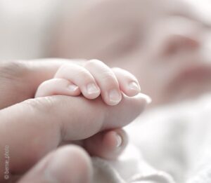 Foto: Die Hand eines Babys umgreift einen Finger. Die Schwangerschaft kann in der Traumdeutung sowohl symbolisch als auch wörtlich gesehen werden.